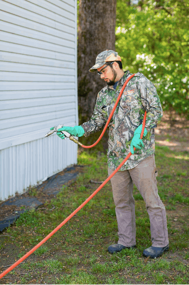 Say Bugman technician treating the exterior foundation line of an East Texas home